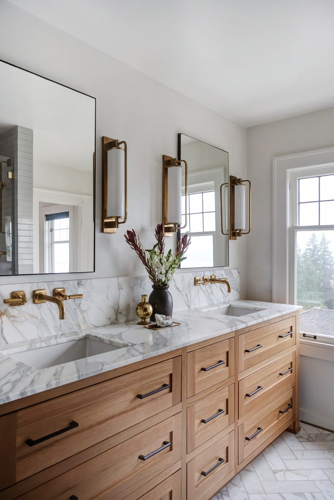 Transitional primary bathroom — marble double vanity with brass sconces