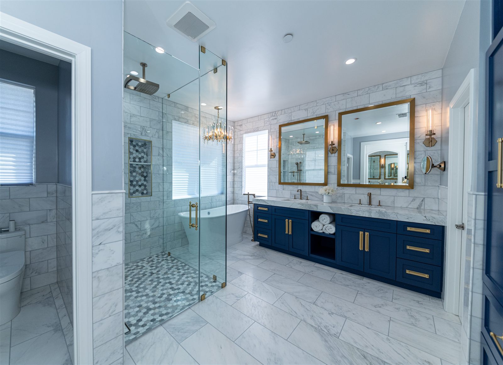 Primary bathroom remodel with marble, navy vanity and brass fixtures
