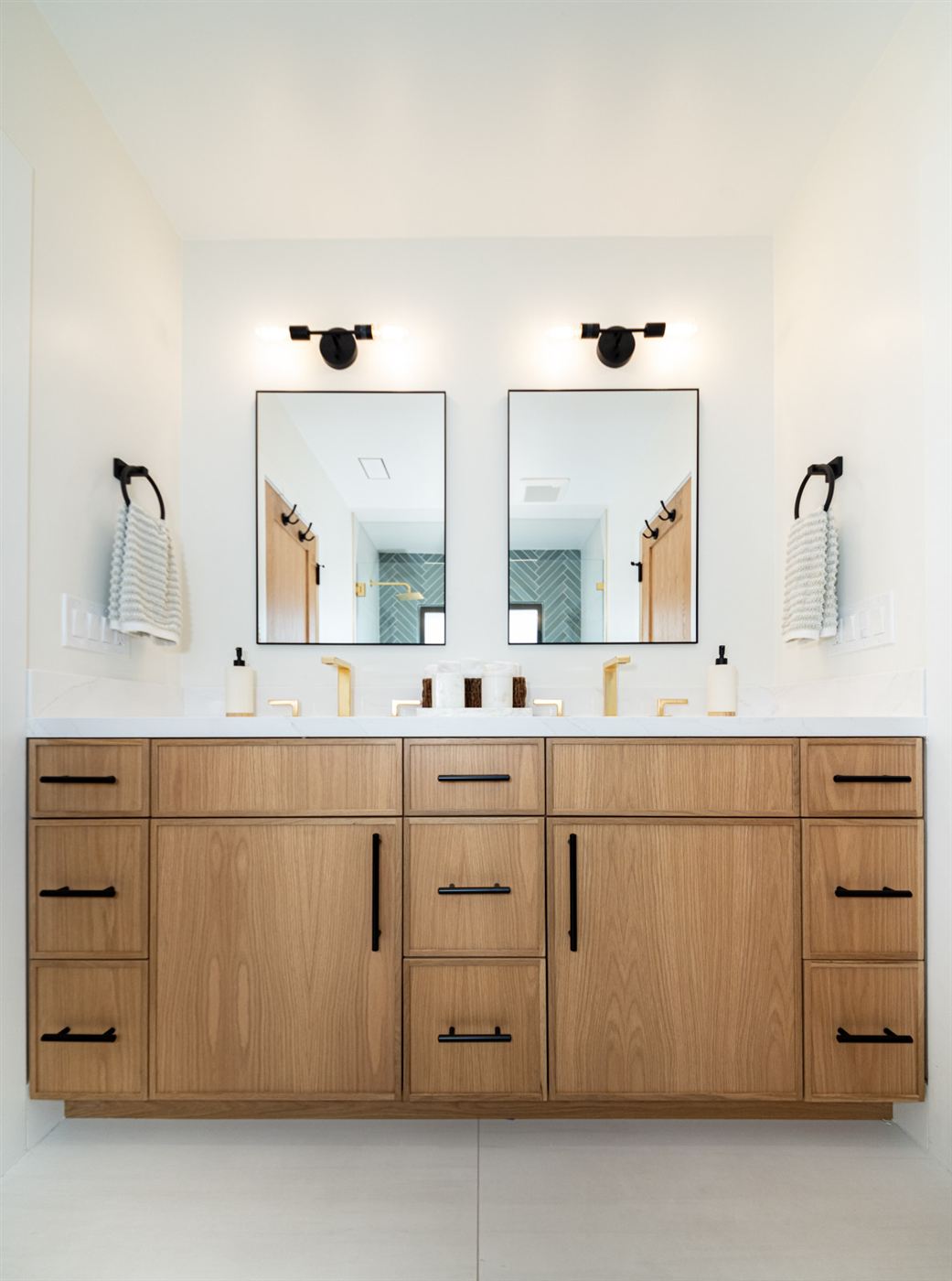 Double vanity with gold faucets and light wood cabinets