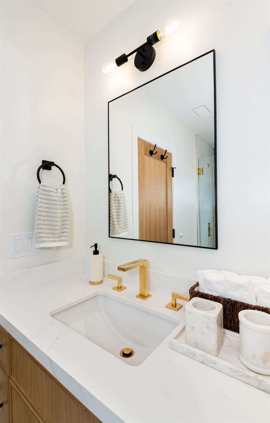 Bathroom with light wood vanity and black-frame mirror