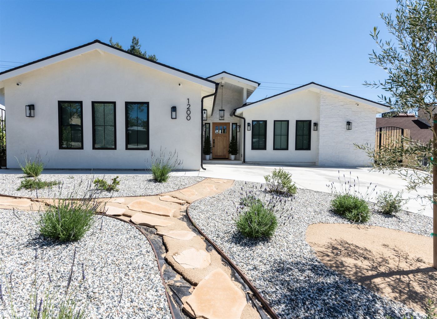 Front exterior of a modern single-story home with white stucco and dark trim