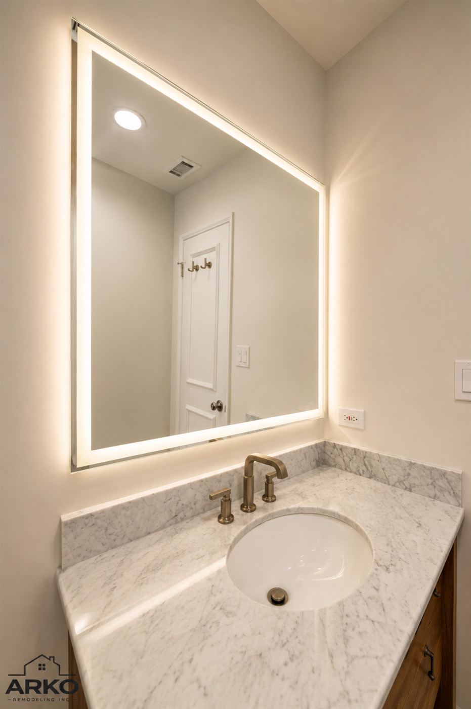 Undermount sink in Carrara-style marble with brass gooseneck faucet