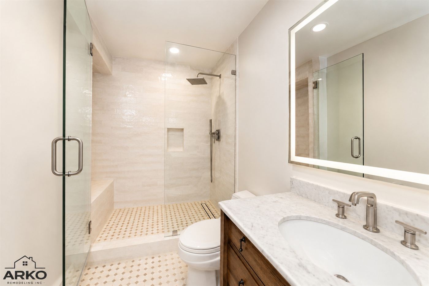 Remodeled primary bathroom with glass shower and wood vanity