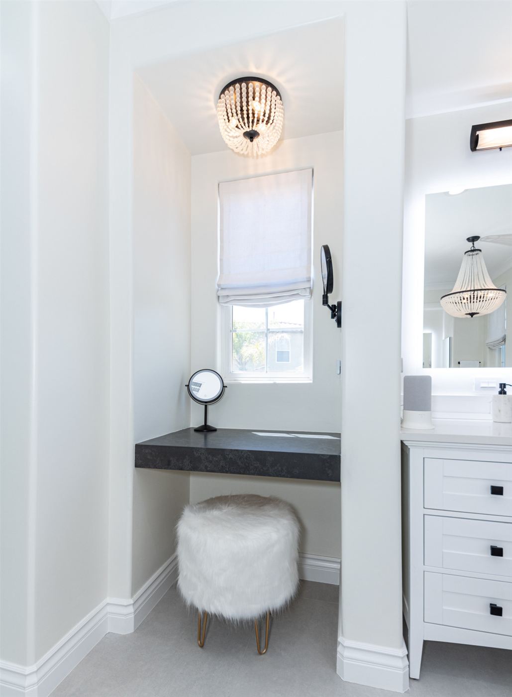 Vanity nook with dark floating countertop and round mirror