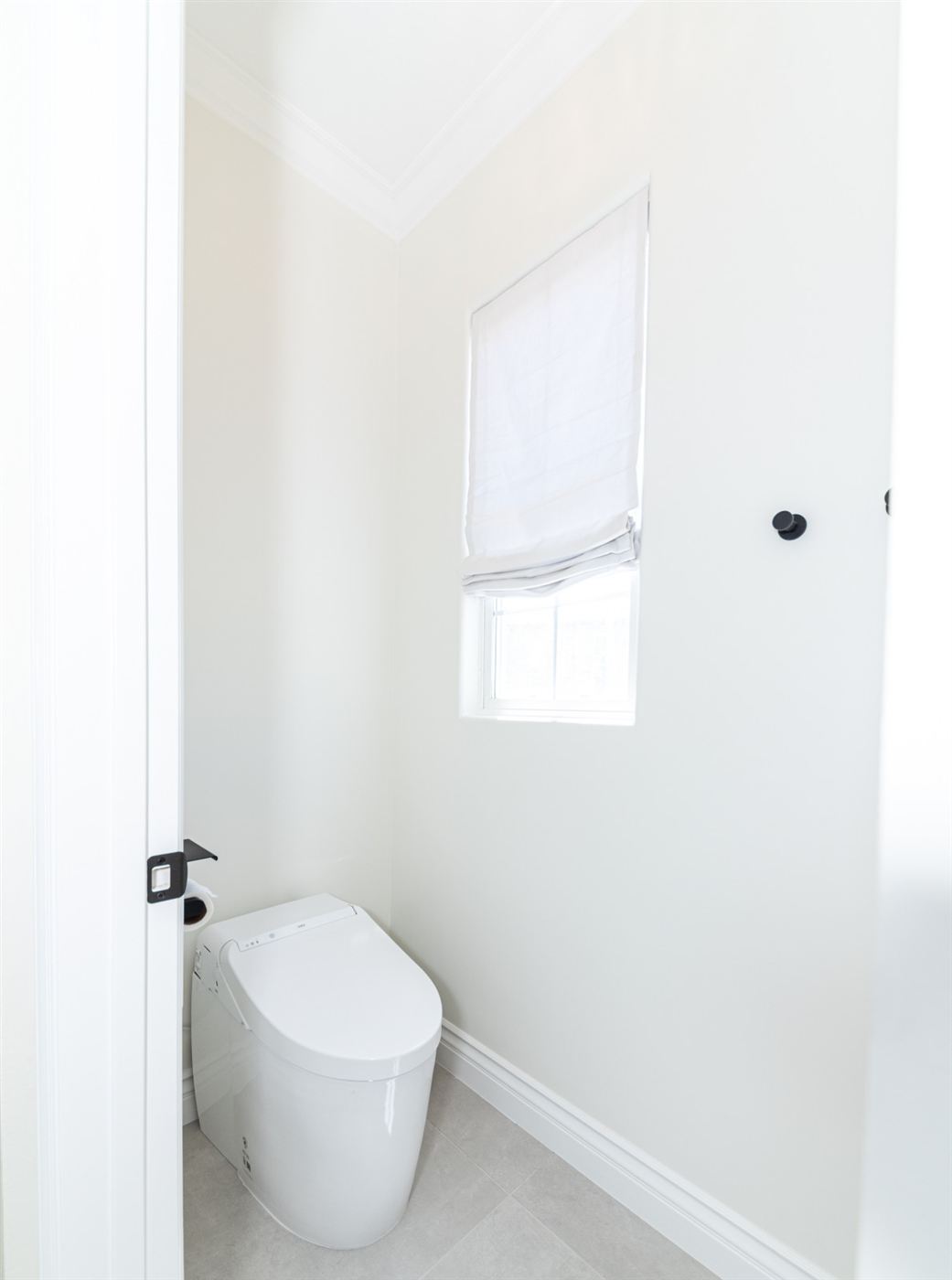 Toilet room with roman shades and grey tiles